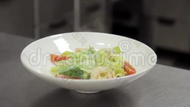 带手套的厨师在沙拉中<strong>加入</strong>虾，在白色盘子中<strong>加入</strong>西红柿。